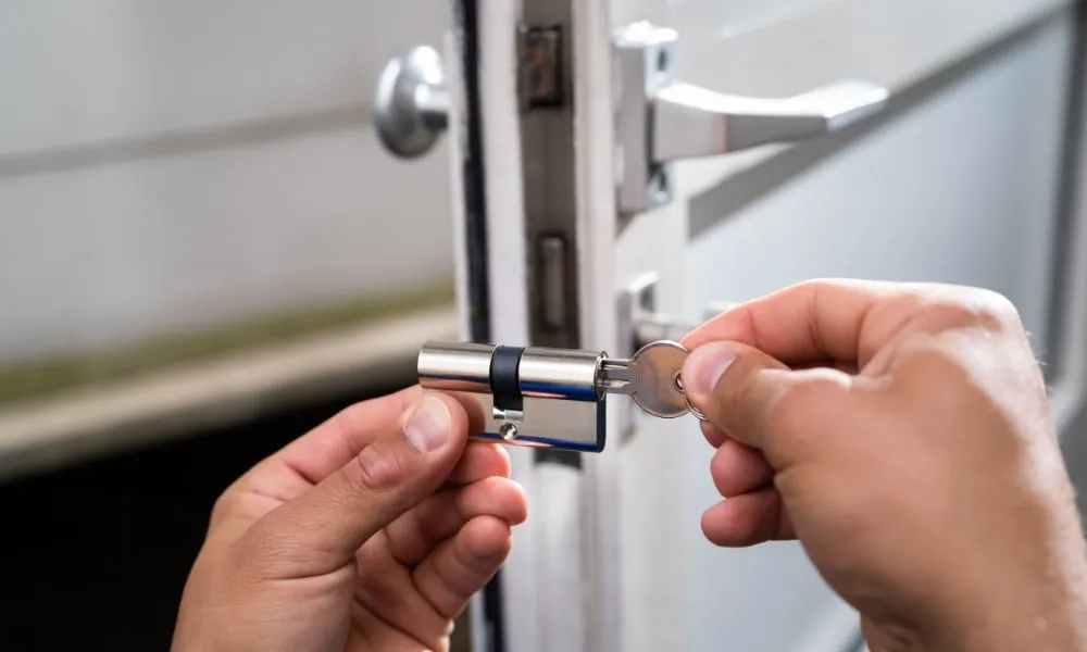 Hands inserting key into door lock cylinder