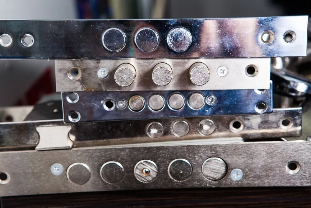 Stacked metal plates with circular magnets and bolts
