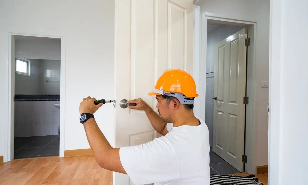 Tradie installing door handle inside home hallway
