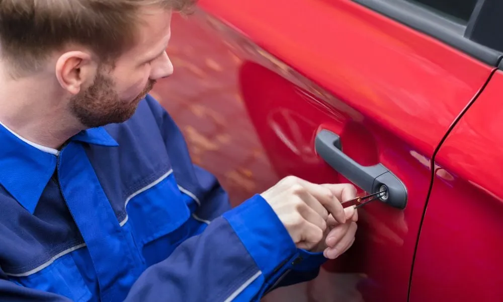 Locksmith unlocking red car door with tools