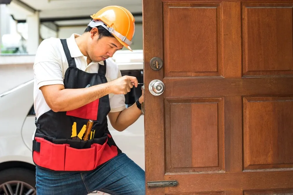 Locksmith repairing a silver door handle lock