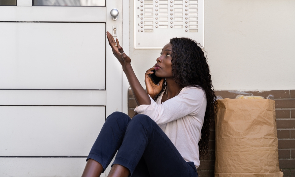 Woman sitting by door with paper bag, calling